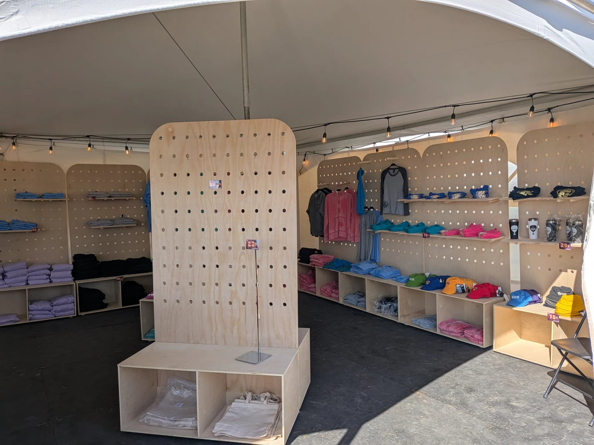 Kiosque marchand en bois aménagé sous un chapiteau, présentoirs et étagères sur mesure