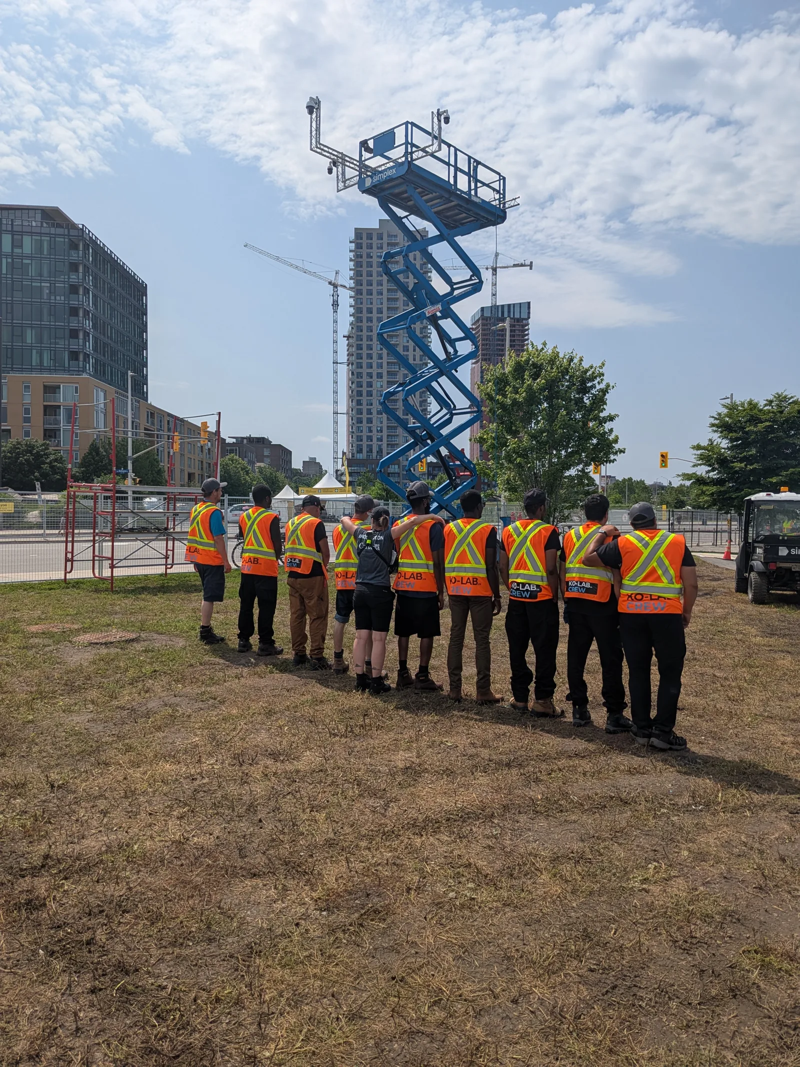 Équipe KO-LAB en gilets de sécurité devant une nacelle à ciseaux, sur un site événementiel en ville